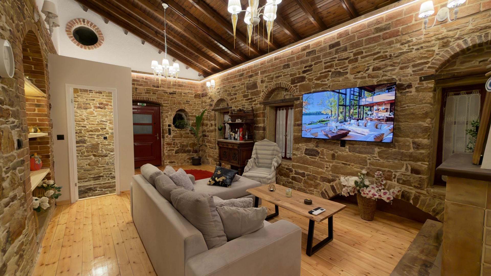 Living room with stone walls, timber ceiling, sofa and TV