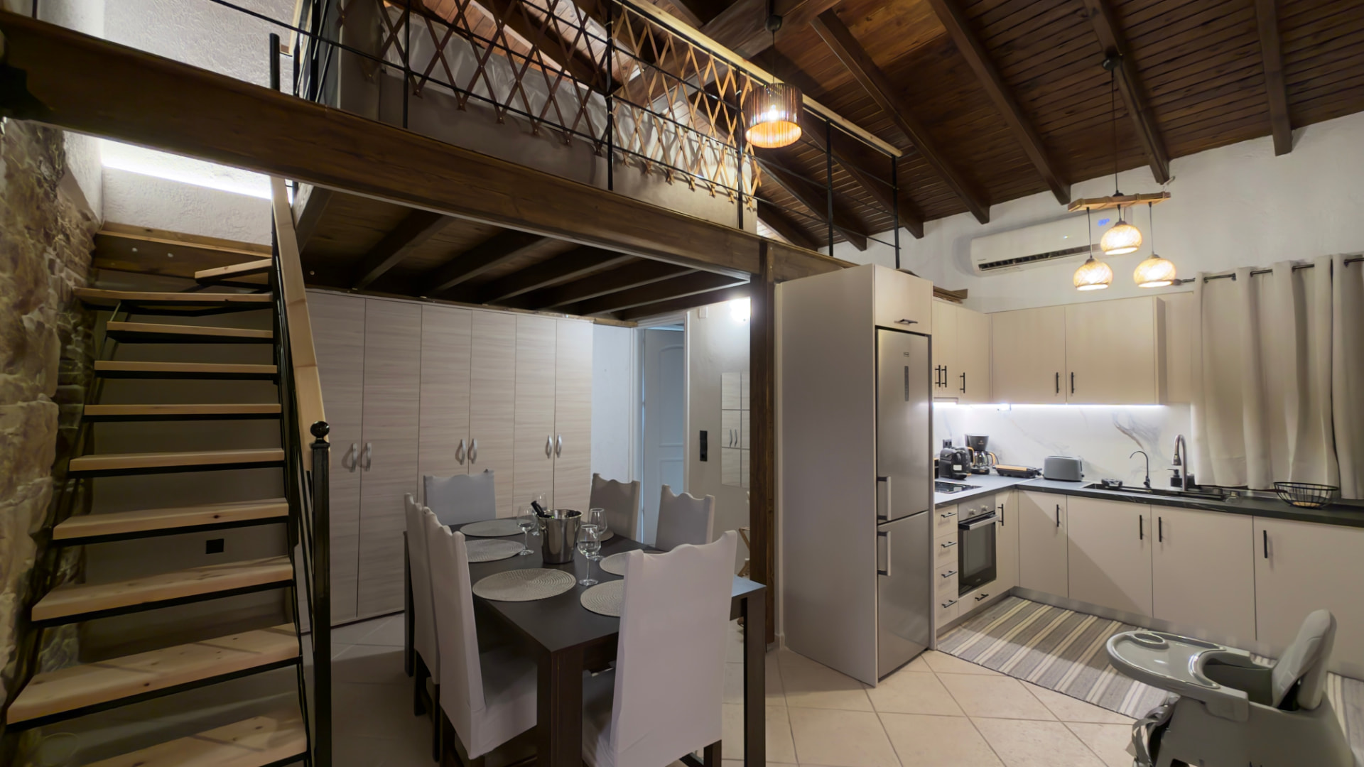 Open-plan kitchen with dining table, wooden staircase and loft with timber ceiling